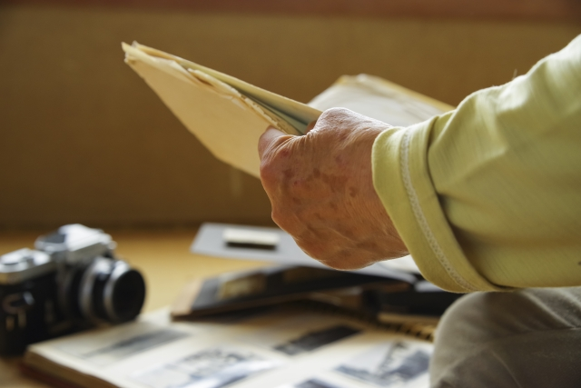 遺品整理で写真などを片付ける高齢者男性の写真